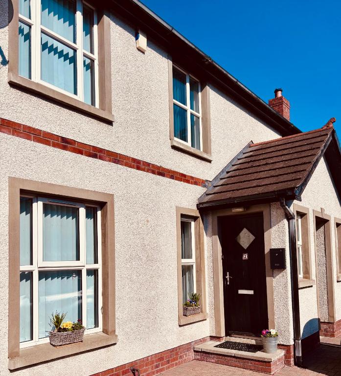 una casa bianca con porta nera e finestre di Beckers Place at No2 NLC in Carrickfergus a Carrickfergus