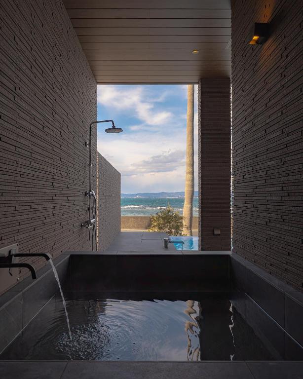 a bathroom with a tub with a view of the ocean at EZRA VILLA shirahama in Shirahama