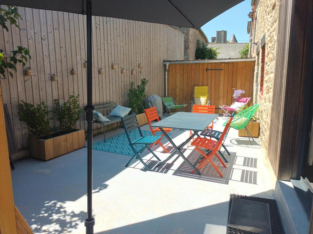 une terrasse avec une table et des chaises sous un parasol dans l'établissement Ker Augustine Maison de pecheur 3 étoiles Clévacances, à Lancieux