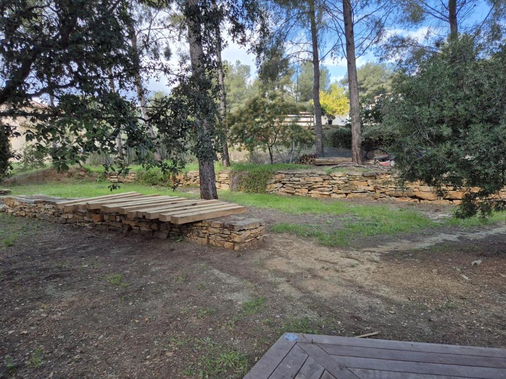 un banc en bois assis sous un arbre dans un parc dans l'établissement Maison l'Oasis 8 personnes piscine, à La Ciotat