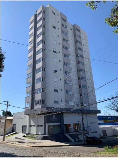 a tall white building on the side of a street at Apto6 com WI-FI e garagem e 100 a av Brasil in Passo Fundo