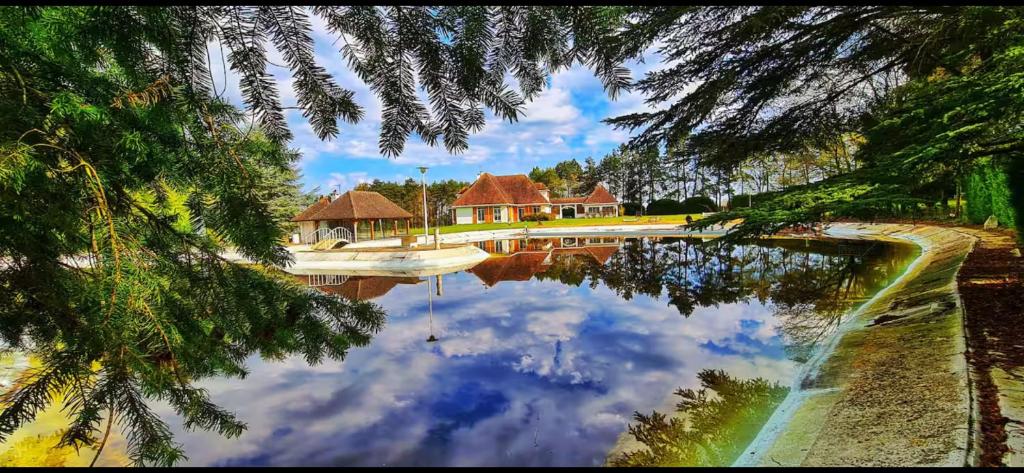 un reflet d'une maison dans un corps d'eau dans l'établissement Domaine idyllique Phamily House, à Senonches