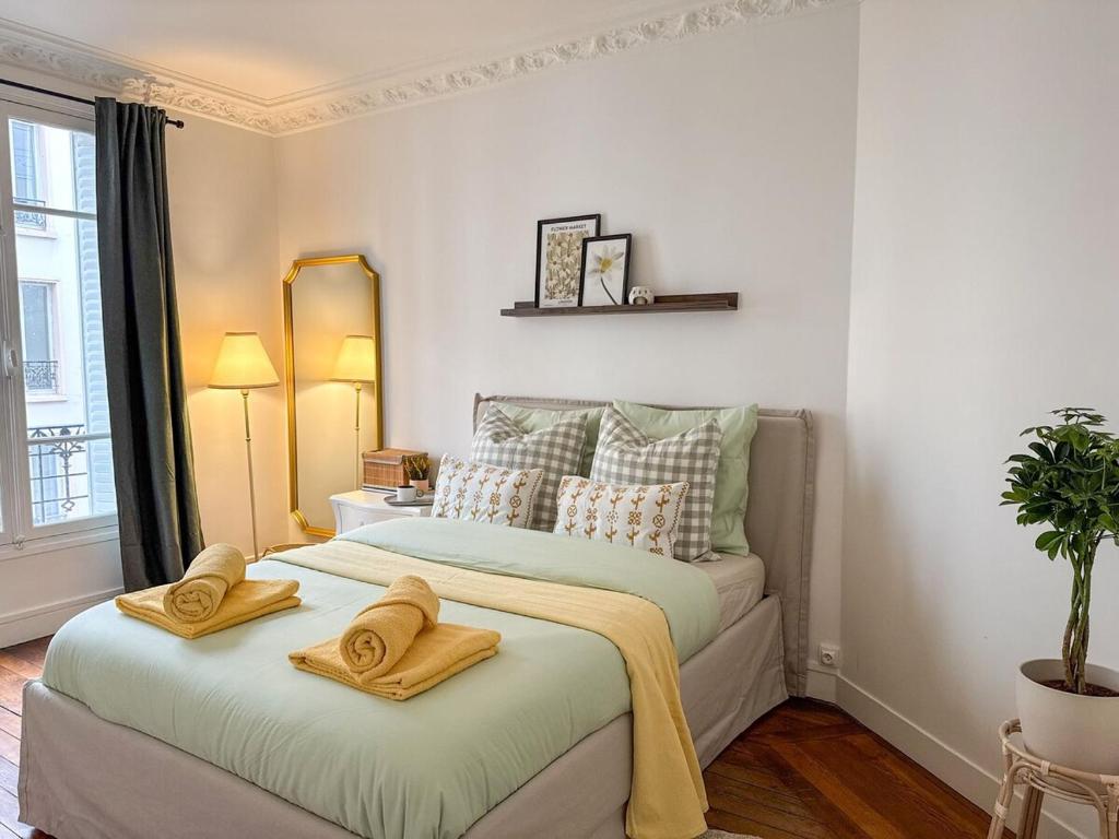 une chambre avec un grand lit avec des serviettes dessus dans l'établissement Parisien Élégant & Calme, à Paris