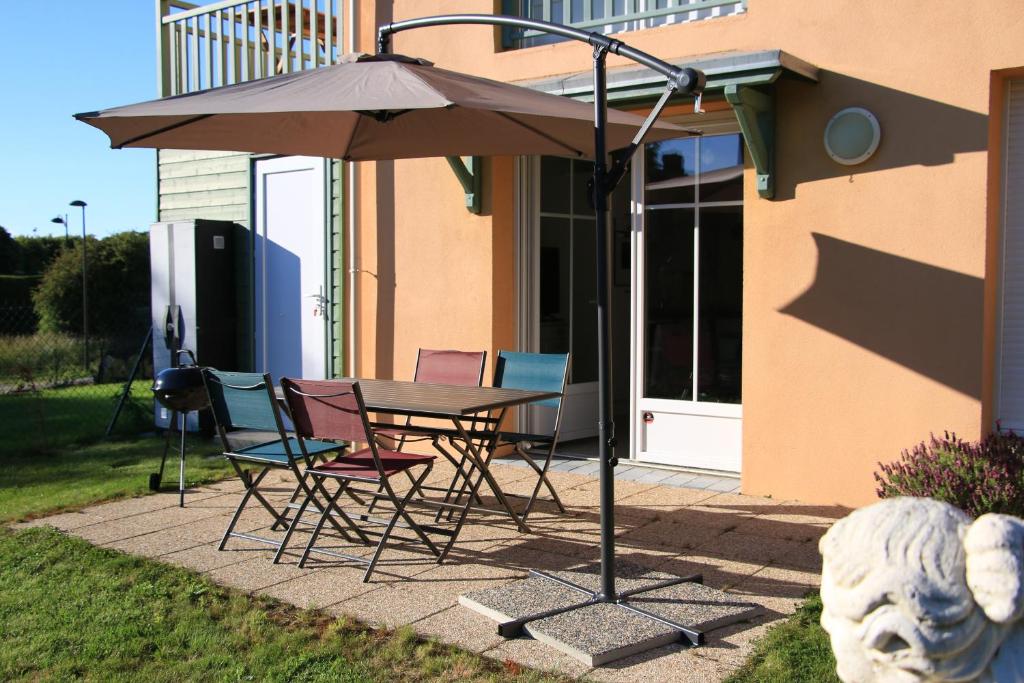 - une table et des chaises avec un parasol en face d'une maison dans l'établissement l' Huîtrier-Pie, à Saint-Valery-sur-Somme