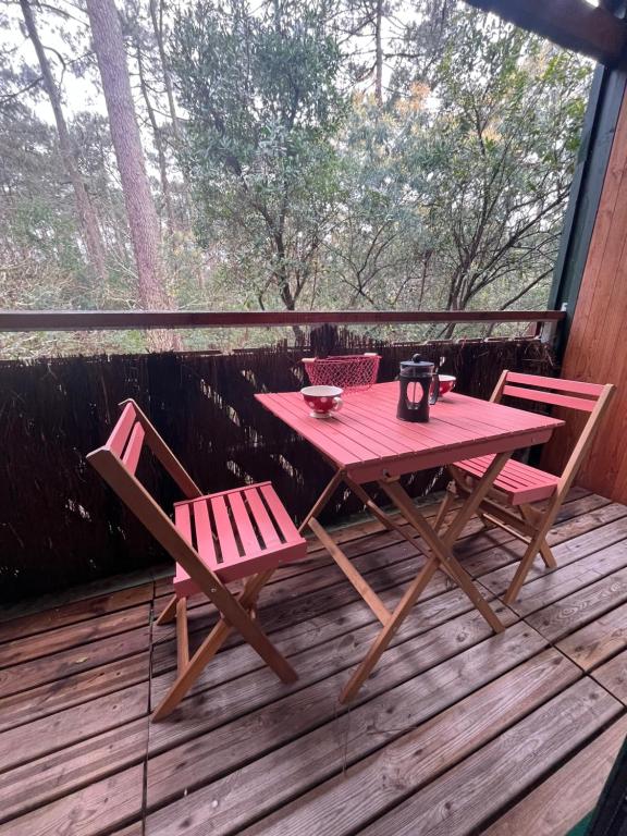 une table de pique-nique et deux chaises sur une terrasse dans l'établissement Séjour nature et détente dans la pinède, à Lège-Cap-Ferret