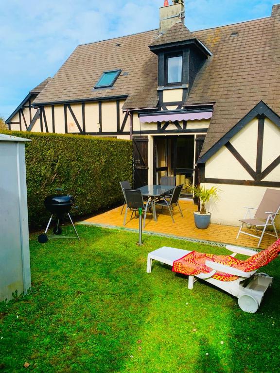 une maison avec un hamac et un barbecue dans la cour dans l'établissement Cottage cosy avec jardin, piscine et parking, à Cabourg