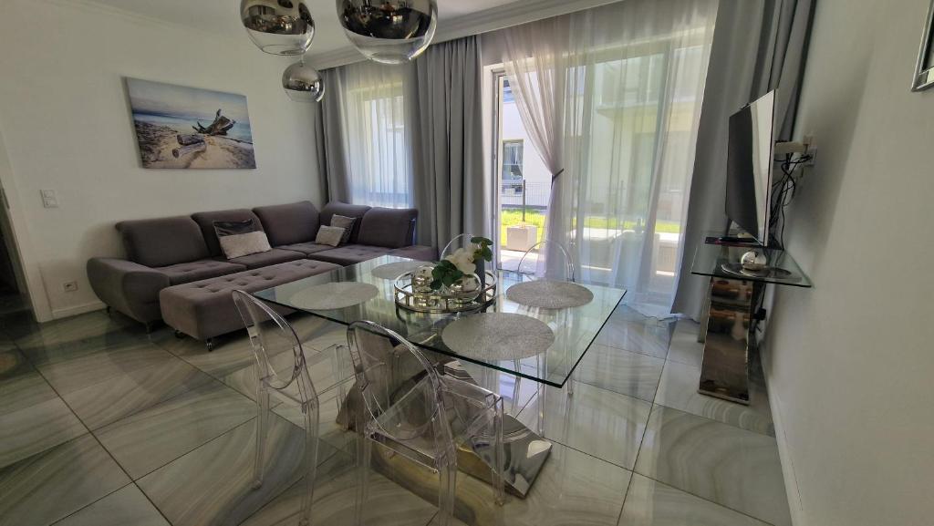un soggiorno con un tavolo di vetro e un divano di Maxim Apartment Pobierowo a Pobierowo