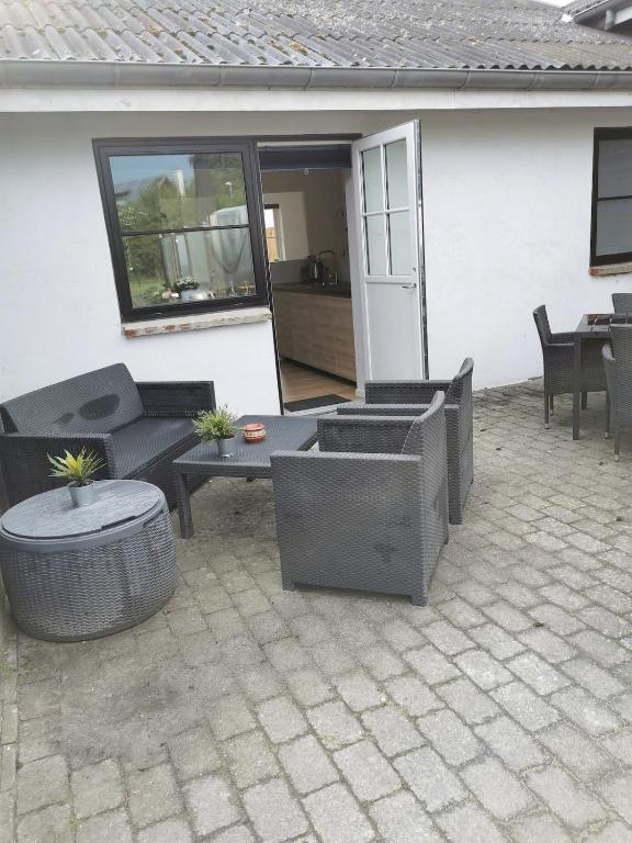 a patio with wicker furniture and a table at Ferielejlighed in Nibe