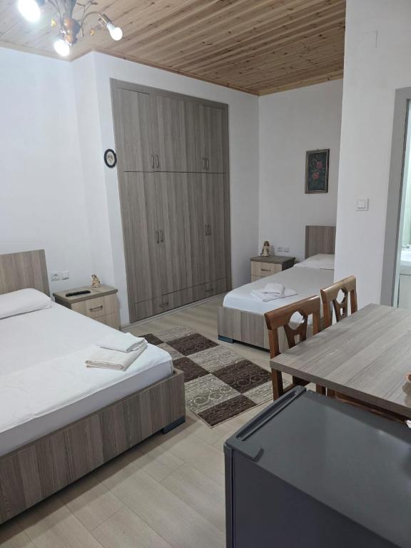 a room with two beds and a table and a tv at Magnolia's Private Room in Gjirokastër