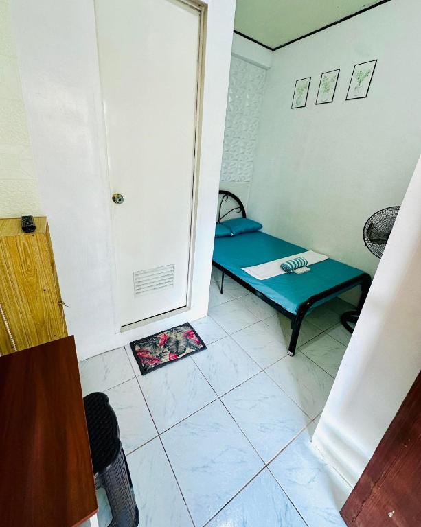 ein kleines Zimmer mit einem Bett und einer Tür in der Unterkunft Wakims Budget Fan Room in Coron