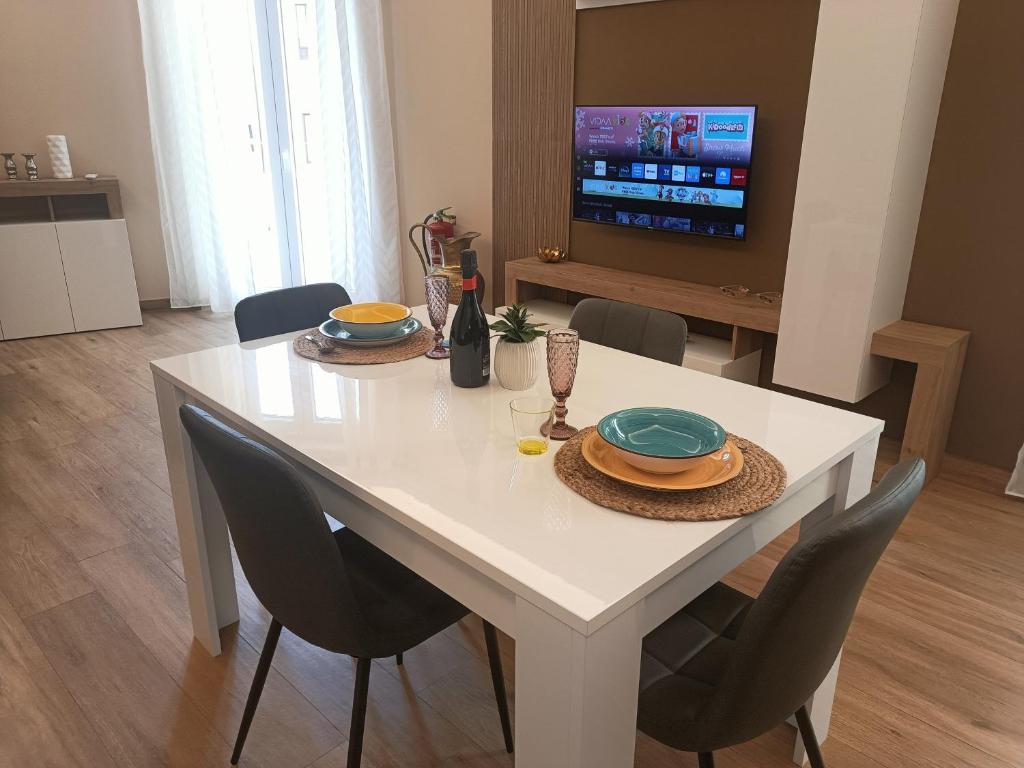 a white table with chairs and a television in a living room at Borgese Apartments in Palermo