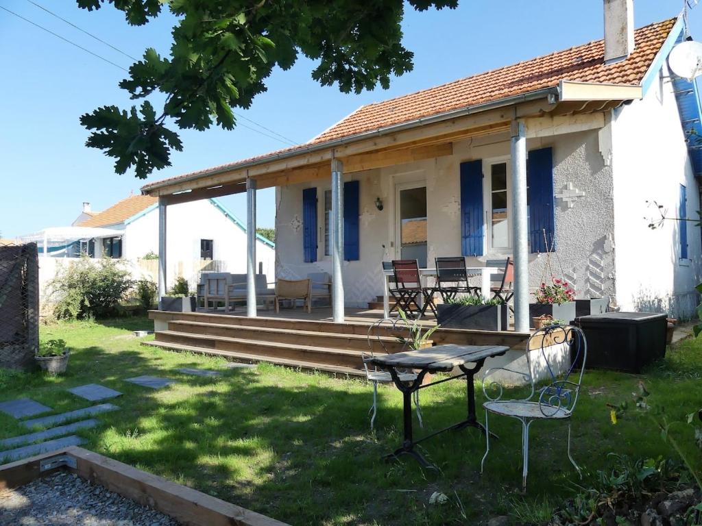 une maison avec une table et des chaises dans la cour dans l'établissement Château d'Oléron La Maison Bleue, au Château-dʼOléron