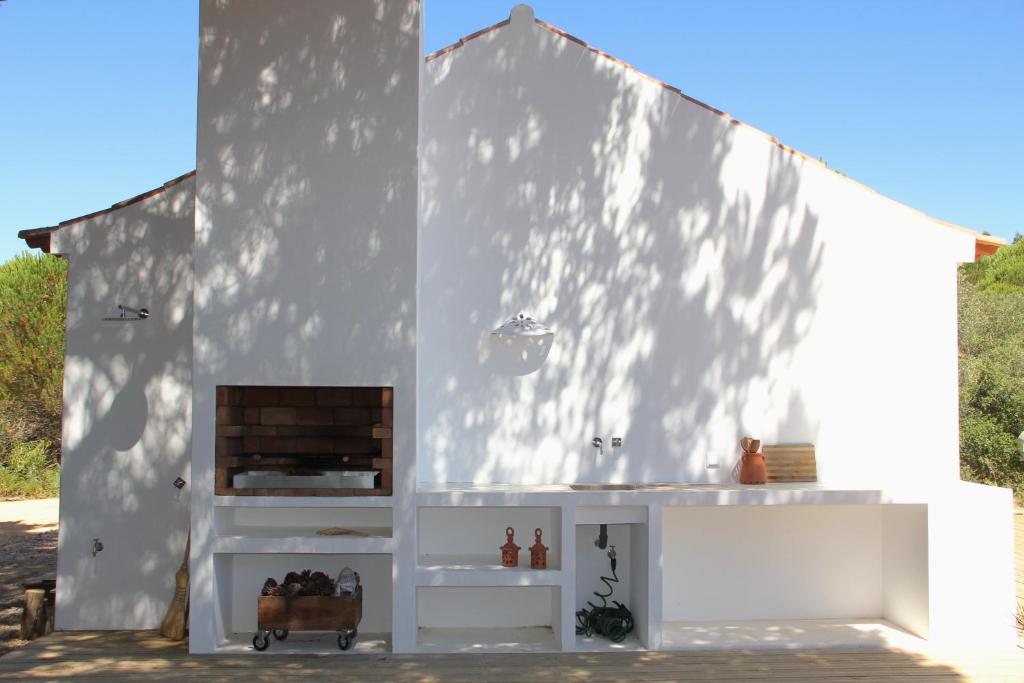 a white building with a fireplace in the middle at Beautiful country home immersed in pine nut farm in São Teotónio