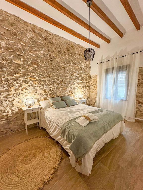 a bedroom with a large bed in a stone wall at Casa Rural Sant Roc in Murla