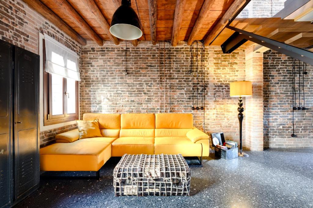 ヴェネツィアにあるGolden Luxe - Glass of Murano luxury apartmentのレンガの壁のリビングルーム(黄色のソファ付)