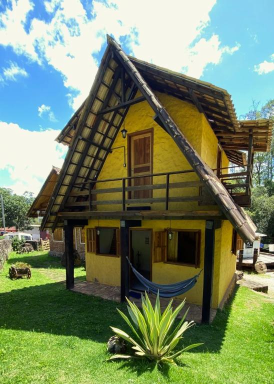 a yellow house with a hammock in front of it at Chalé Topázio in Ouro Preto