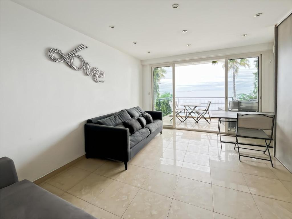 un salon avec un canapé noir et une table dans l'établissement Studio Front de mer, à Antibes