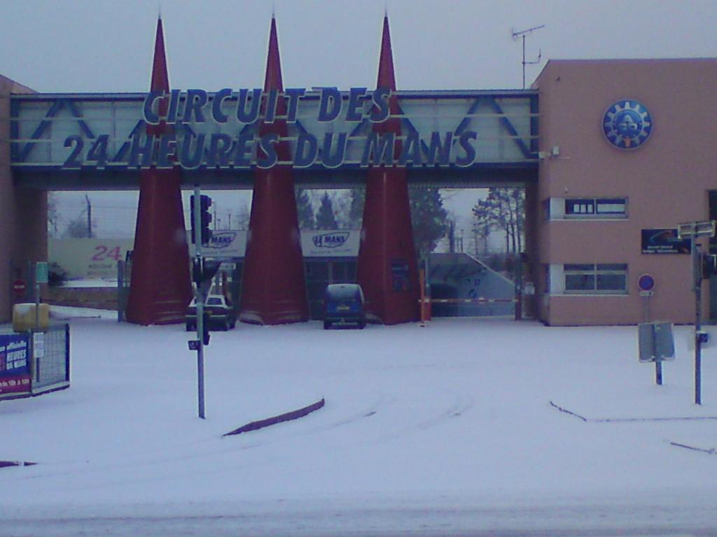 un parking couvert de neige en face d'un bâtiment dans l'établissement places 24 heure du mans plus logement, au Mans