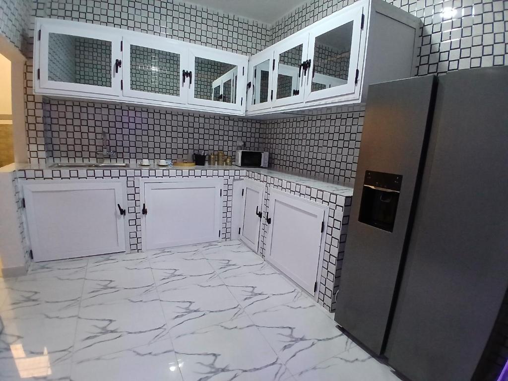 a kitchen with white cabinets and a marble floor at SKA Zac Mbao in Rufisque