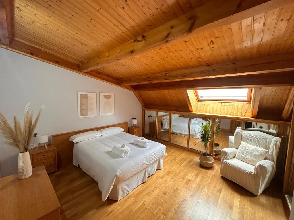 ein großes Schlafzimmer mit einem Bett und einem Stuhl in der Unterkunft Dúplex León Centro in León