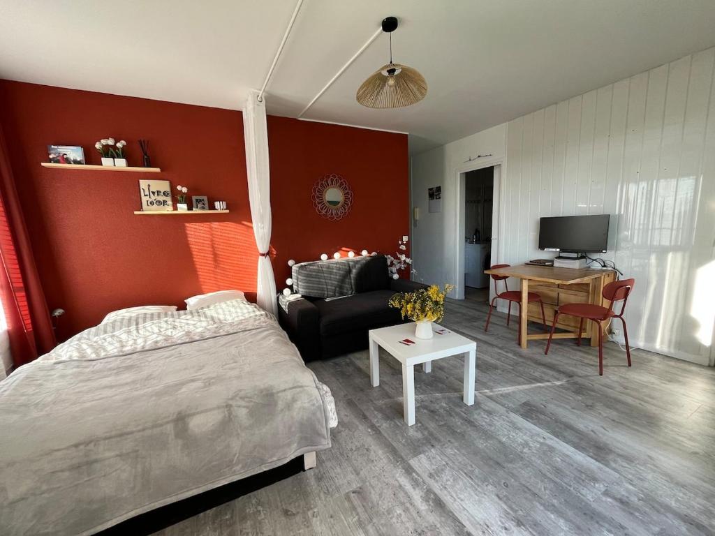 a bedroom with a bed and a couch and a table at Studio et terrasse près de Paris in Suresnes