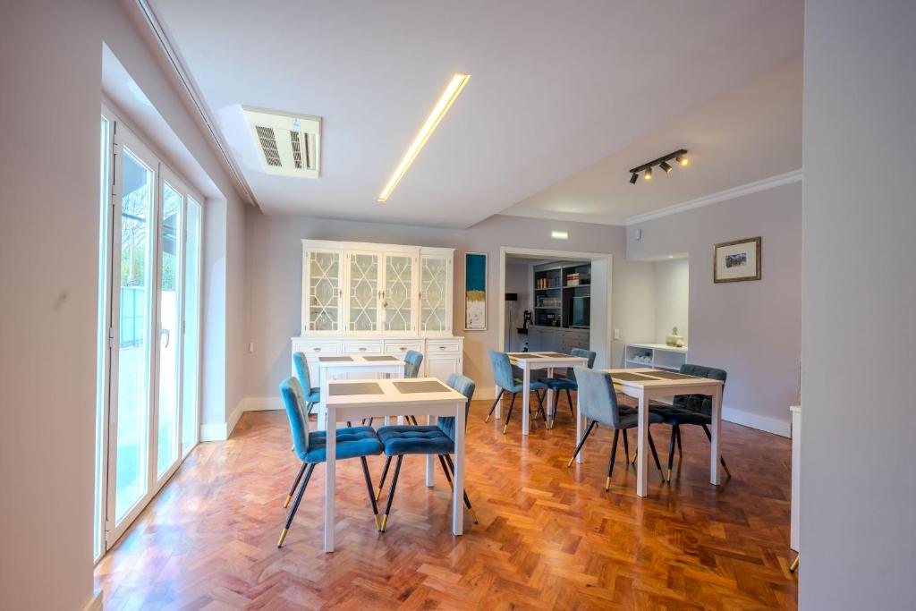 A bright dining room with blue chairs, small tables and doors opening toward the outside.