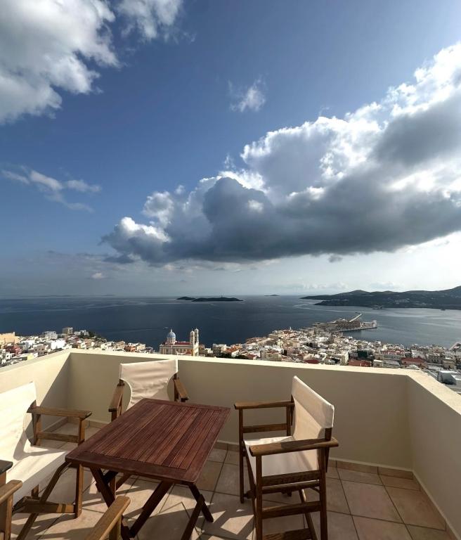 a balcony with a table and chairs and a view of the city at SyrasView in Ermoupoli