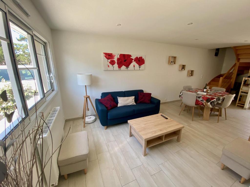 un salon avec un canapé bleu et une table dans l'établissement Cabine de la plage, à Bréhal
