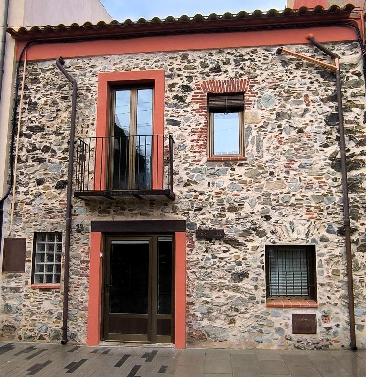 a stone building with a balcony and a door at Ca LA LIDIA GARRIGUELLA in Garriguella