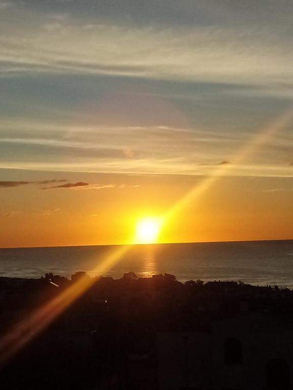 a sunset over the ocean with the sun setting at Il Sole Baunei by the sea in Santa Maria Navarrese