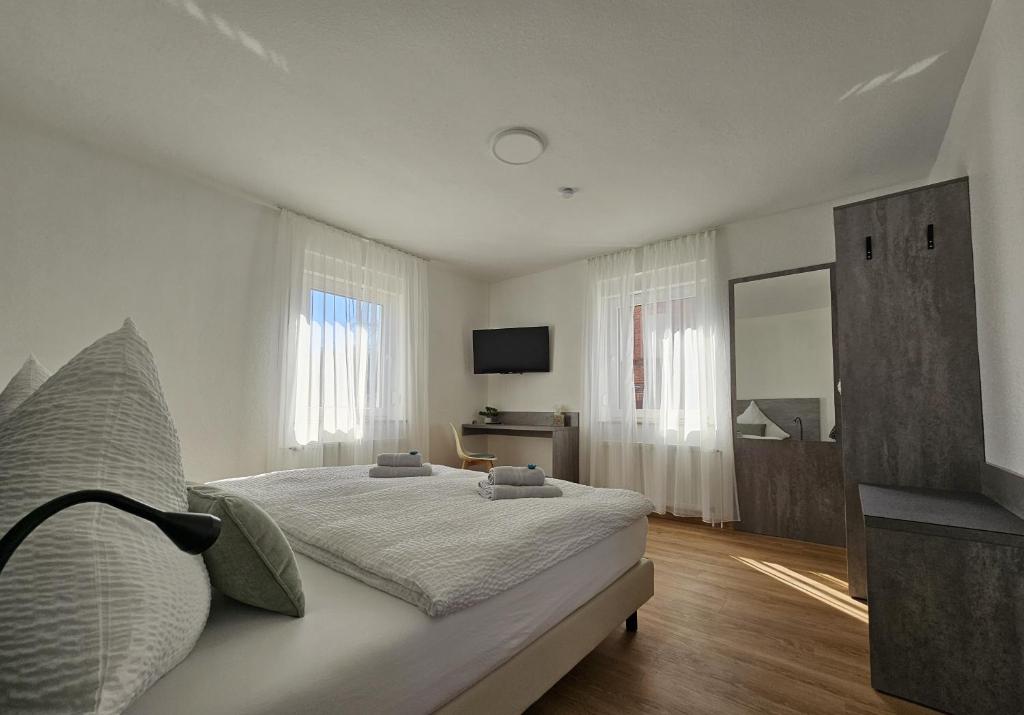 a white bedroom with a bed and a television at Regenbogen8 Ferienwohnungen in Linsengericht
