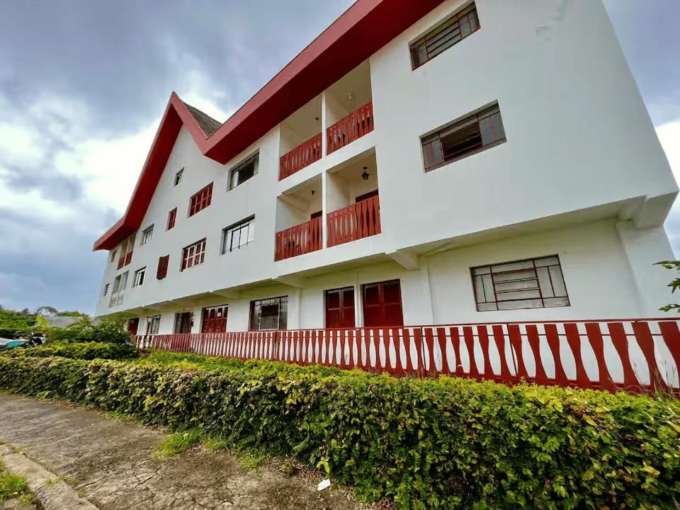 un bâtiment blanc avec des parures rouges et une clôture dans l'établissement Apartamento próximo aos principais pontos turísticos, à Águas de Lindóia