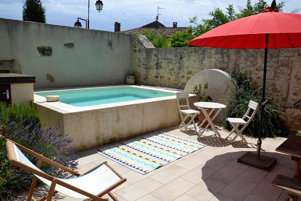 a pool with chairs and a table and an umbrella at Maison de Charme, patio et piscine, wifi in Aujargues
