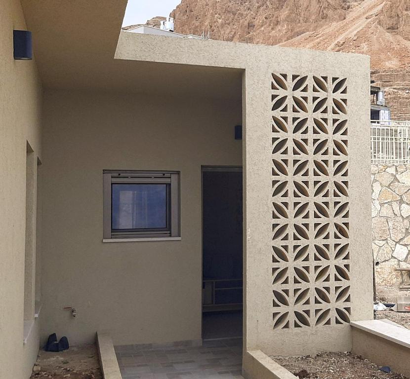 a house with a wall with a geometric design on it at מול ים המלח in Ovnat