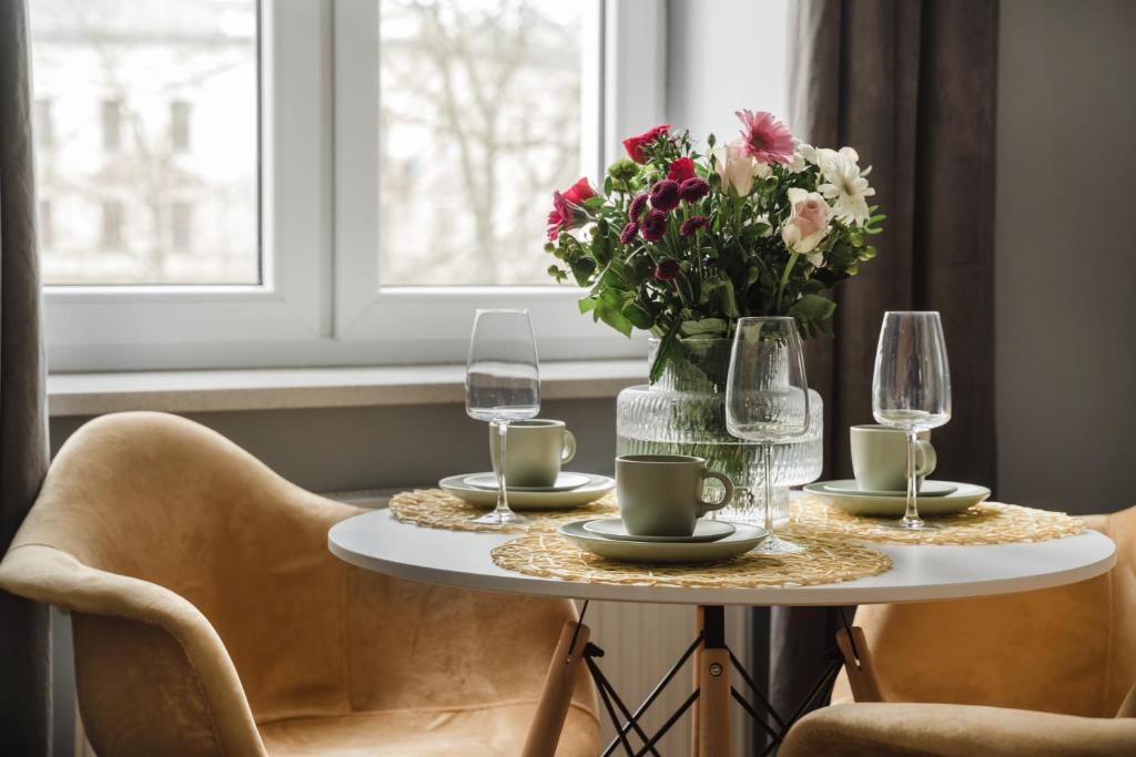 a table with a vase of flowers and wine glasses at Alpari Wawel in Kraków