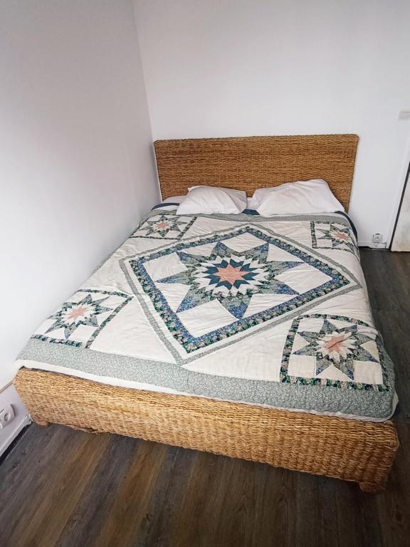 Una cama con una colcha encima en una habitación. en APPARTEMENT MEUBLE, Proche PARIS PROCHE DISNEY, en Neuilly-sur-Marne