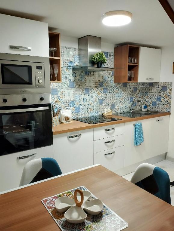 a kitchen with a wooden table with chairs and a microwave at Casa Linda Av in Avola
