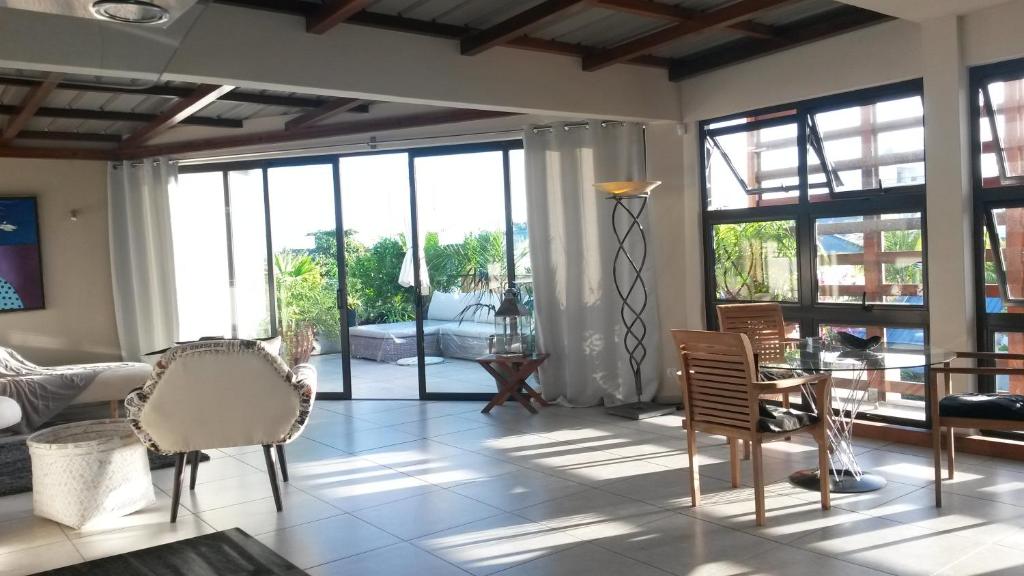 a living room with chairs and a table and windows at Apartment Atrium in Grand Baie