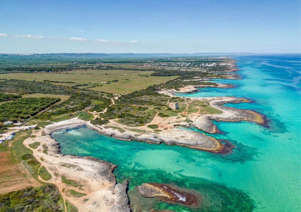 an aerial view of a beach with rocks and water at Ostuni Torre Pozzelle Open Air in Ostuni Costa Merlata