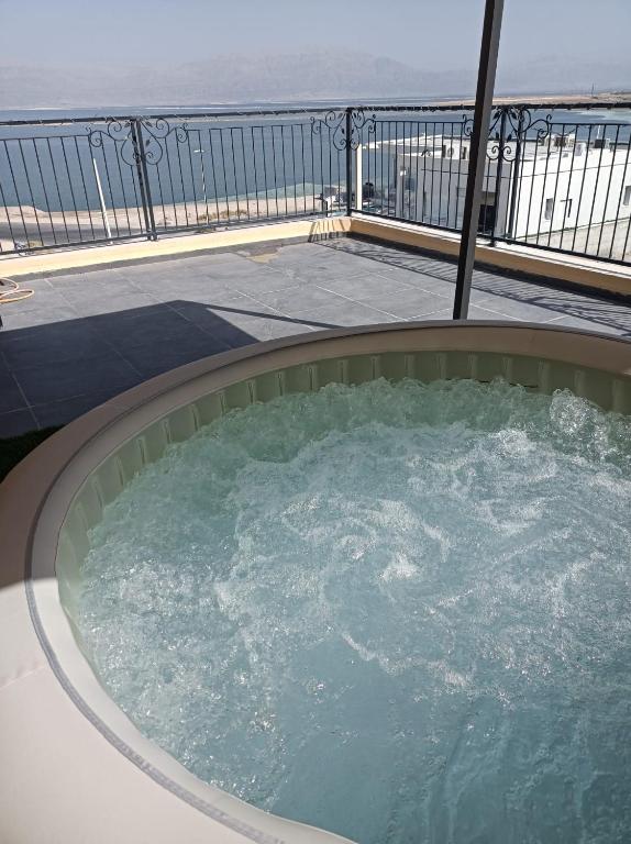 a hot tub on a balcony with the ocean in the background at מול ים המלח זוהר במדבר in Neve Zohar