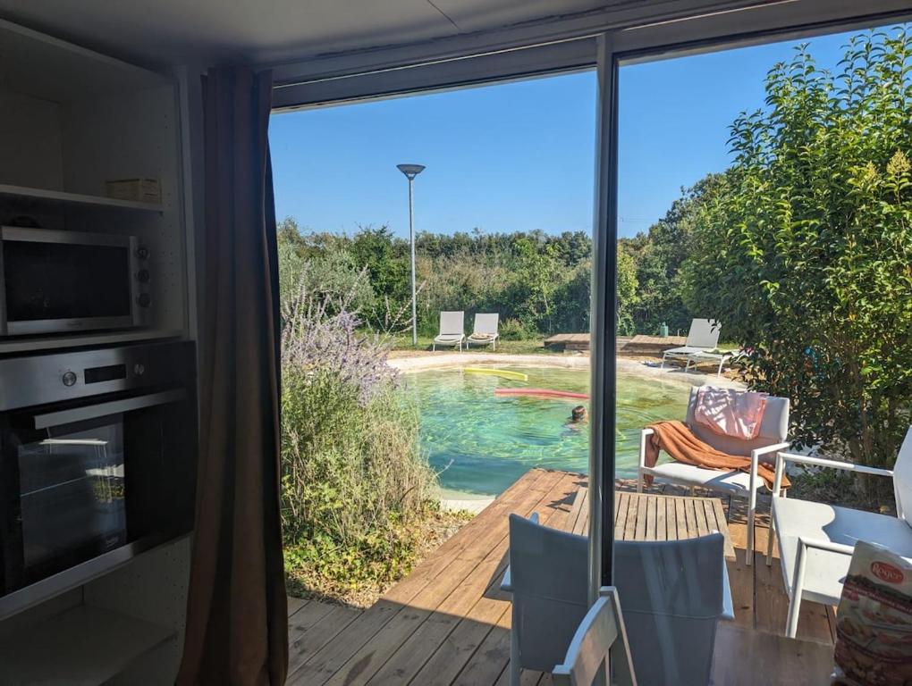 une pièce avec une porte coulissante en verre donnant sur une piscine dans l'établissement Cottage with Natural Pool, à LʼIsle-sur-la-Sorgue