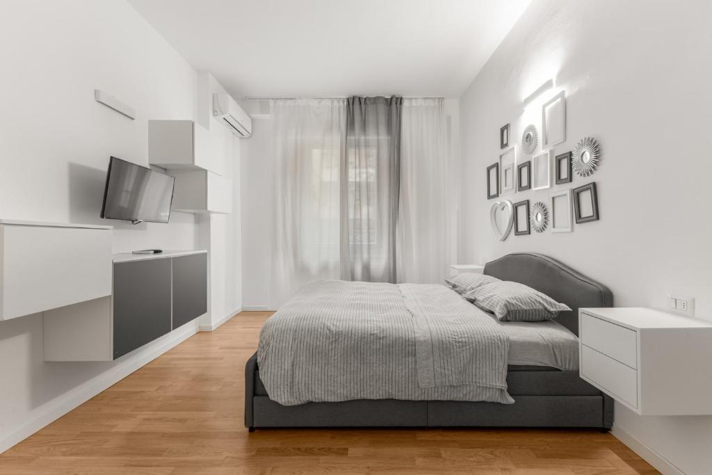 ein weißes Schlafzimmer mit einem Bett und einem Fernseher in der Unterkunft Casa San Siro-Stadio - Stadio e Metropolitana in Mailand
