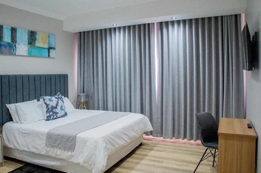 une chambre avec un lit, une chaise et une fenêtre dans l'établissement Bokwe's Guest House- Cape Town, à Gordons Bay