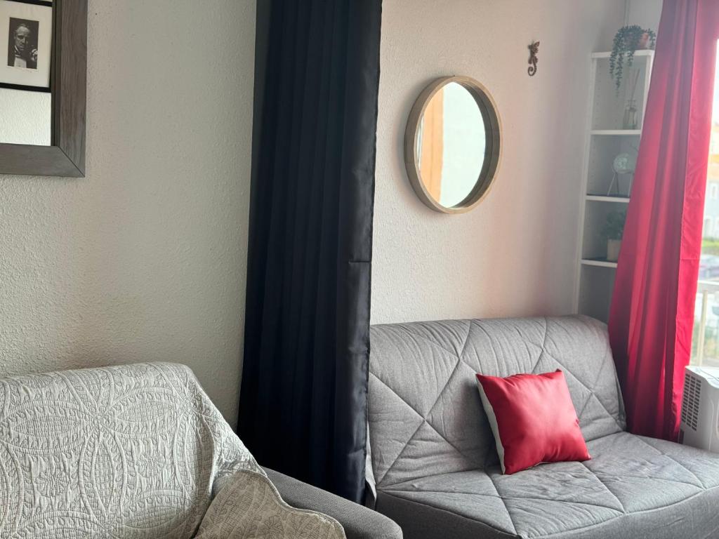 Cette chambre comprend un fauteuil gris avec un oreiller rouge. dans l'établissement Avant port, au Cap d'Agde