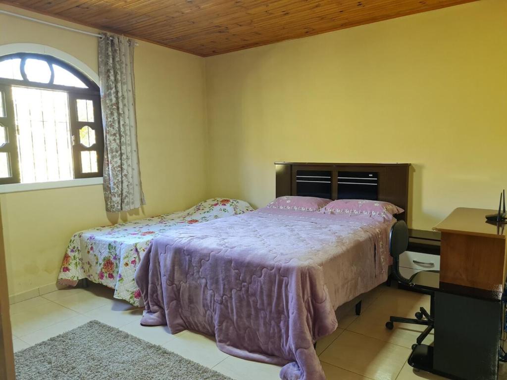 a bedroom with a bed and a desk and a window at Hospedagem Aracê in Domingos Martins