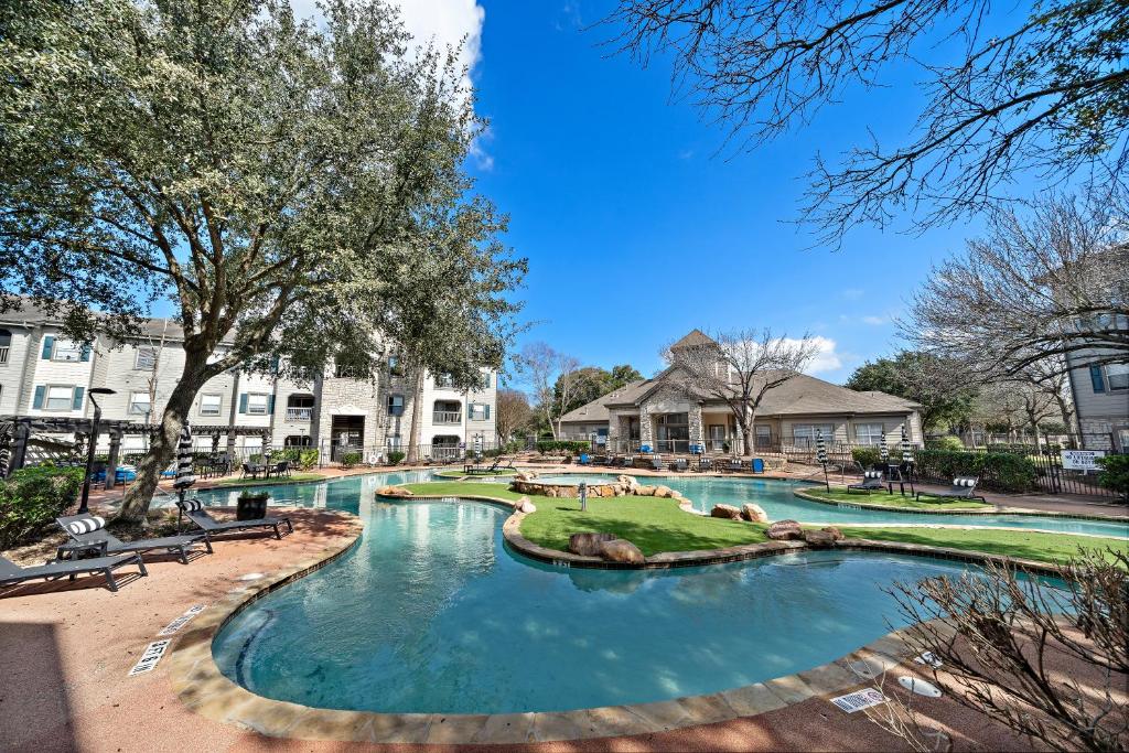 a pool at a resort with benches and trees at Houston Lakeside Living in Houston