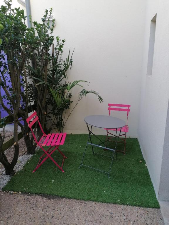 deux chaises roses et une table sur un carré d'herbe dans l'établissement Studio Sardinerie, à La Rochelle