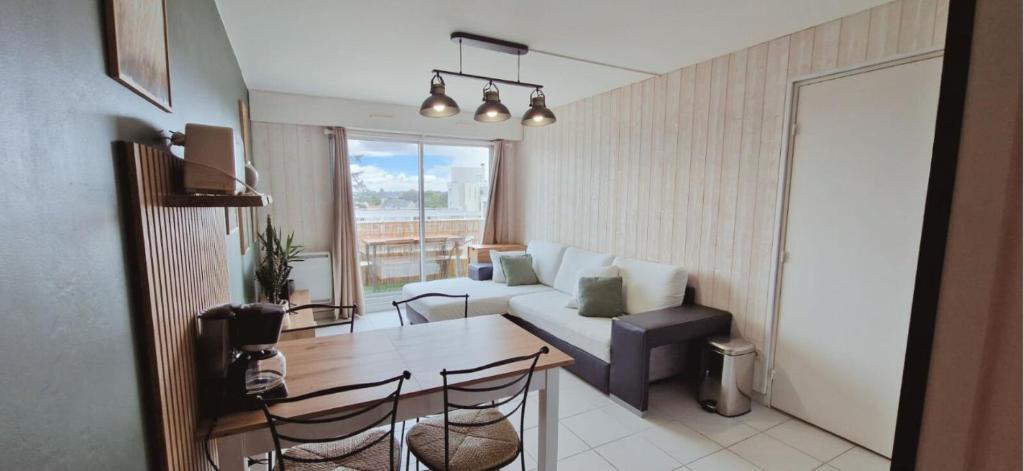 un salon avec un canapé et une table avec des chaises dans l'établissement Le Cœur des Océanes, à Pornichet