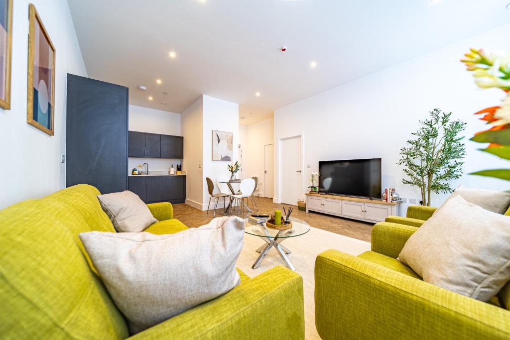 a living room with a yellow couch and a tv at The Essex Apartments - Ashby House in Chelmsford