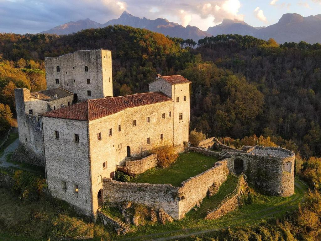 an old castle on a hill with mountains in the background at Glamping Castel Dell'Aquila in Gragnola